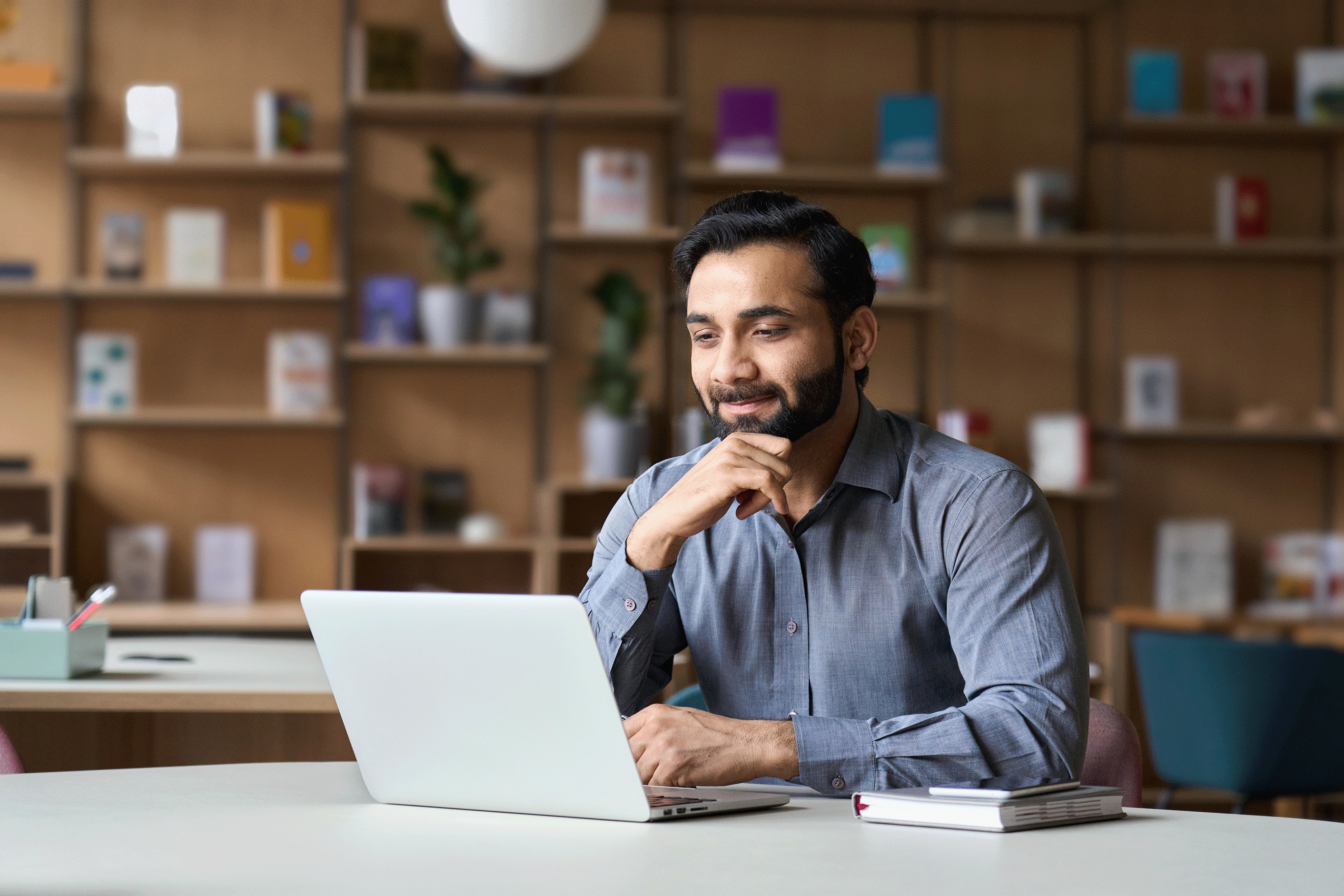 Man-Sitting-At-White-Desk-Using-Laptop